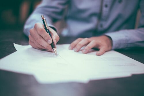 A person reviewing and signing compliance documents at a desk