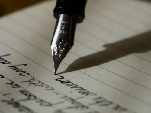 A fountain pen writing on lined paper